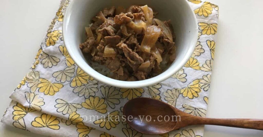 白い器に盛られた牛丼と木製スプーン、調理と保存の工夫を伝える家庭的な雰囲気の写真 